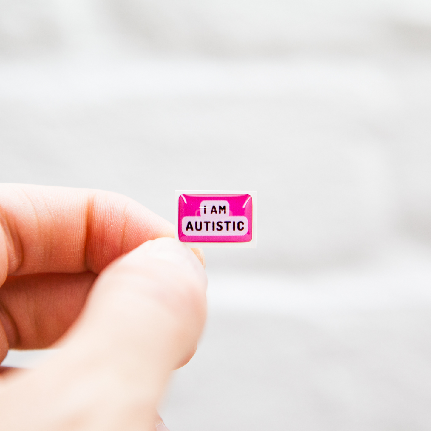 A high-quality autistic sticker with bold text saying "I Am Autistic" in pink or blue, designed for name badges and ID badges, promoting autism awareness and inclusivity.