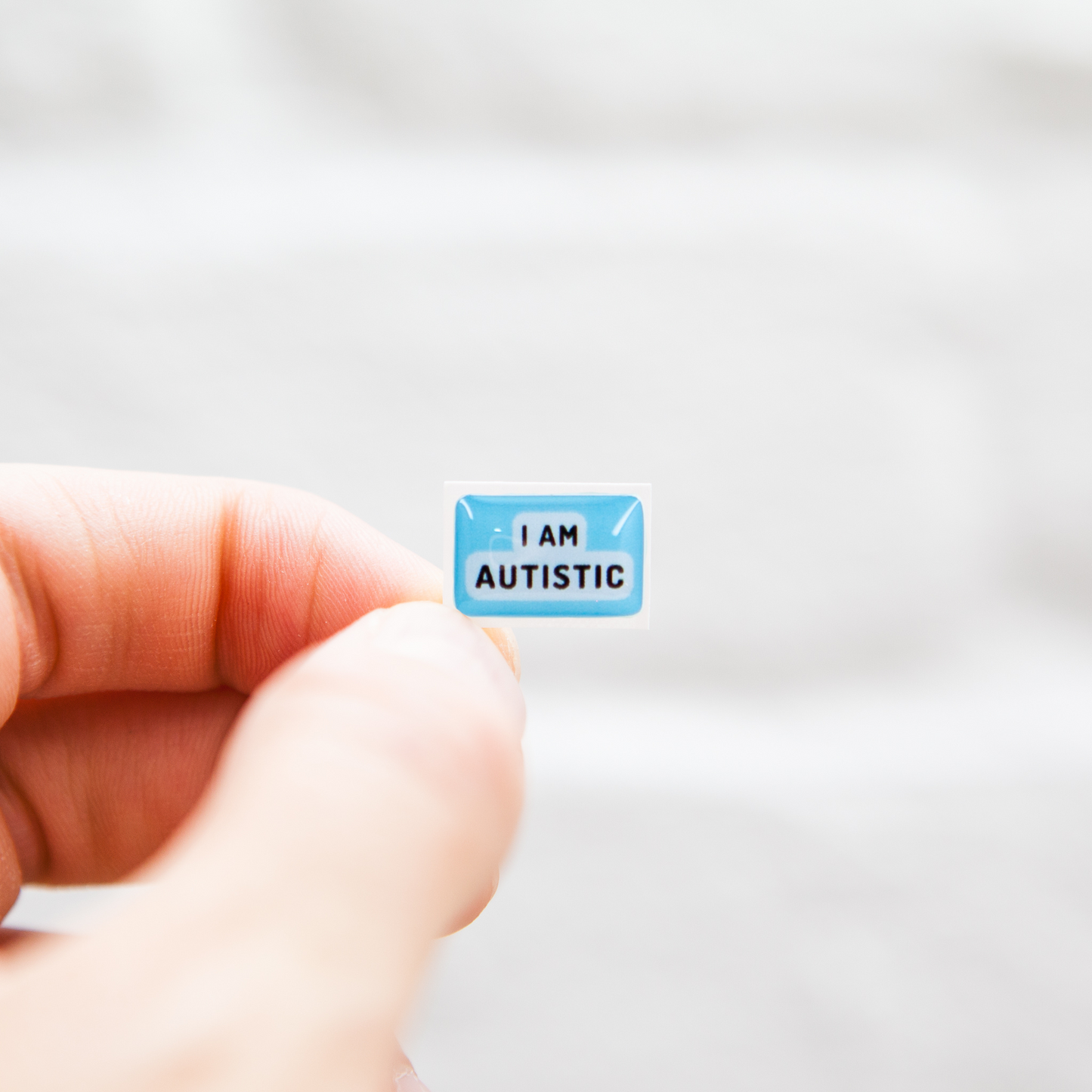 A high-quality autistic sticker with bold text saying "I Am Autistic" in pink or blue, designed for name badges and ID badges, promoting autism awareness and inclusivity.