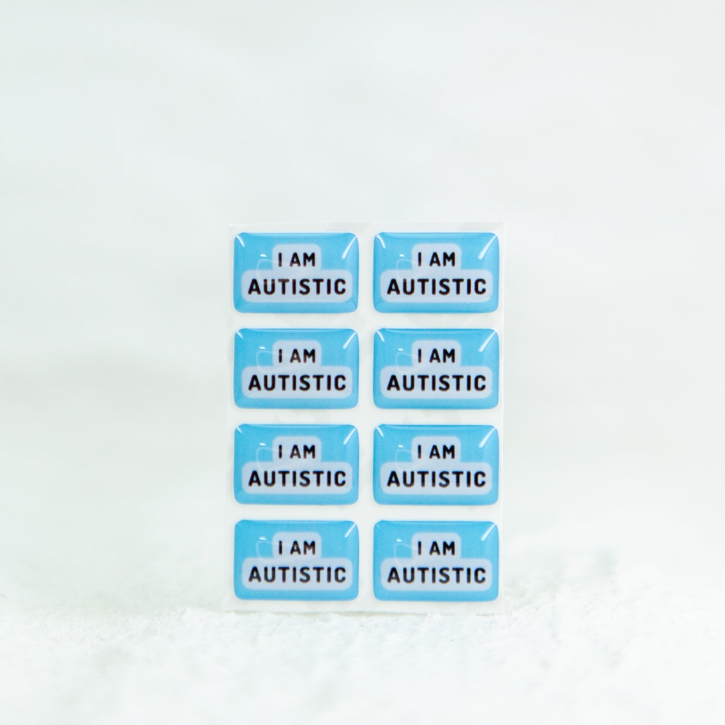 A high-quality autistic sticker with bold text saying "I Am Autistic" in pink or blue, designed for name badges and ID badges, promoting autism awareness and inclusivity.