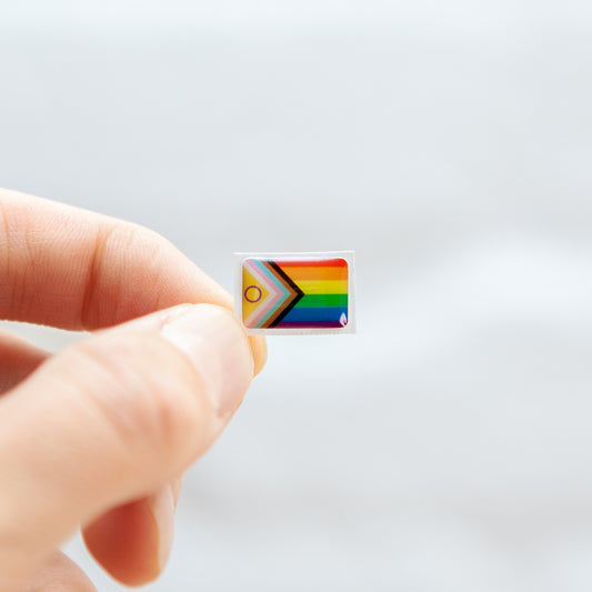 A vibrant sticker featuring the Progress Pride and Intersex Flag design for name badges and ID tags. A high-quality LGBTQIA+ pride flag sticker with super-sticky adhesive.