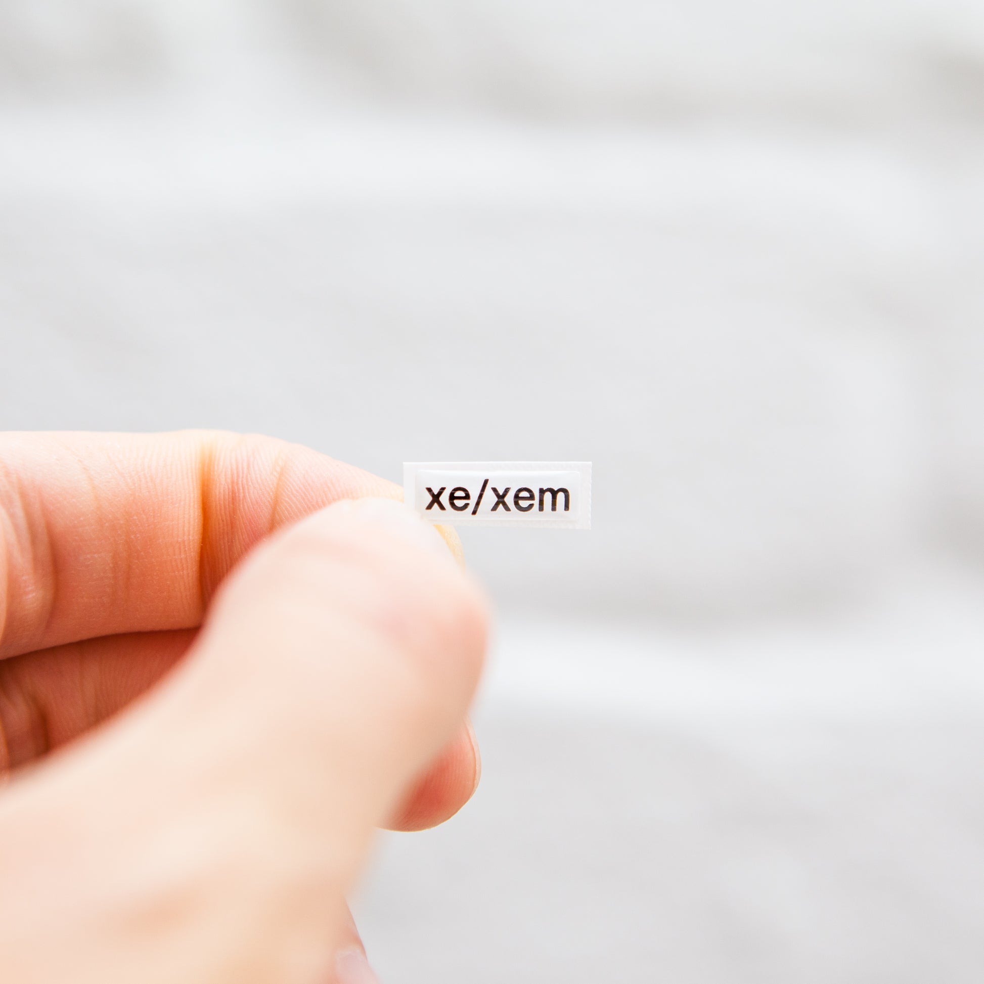 A white sticker with black text displaying xe/xem pronouns, designed for name badges and ID tags. A high-quality pronoun sticker with durable epoxy resin. This pronouns sticker for name badges.