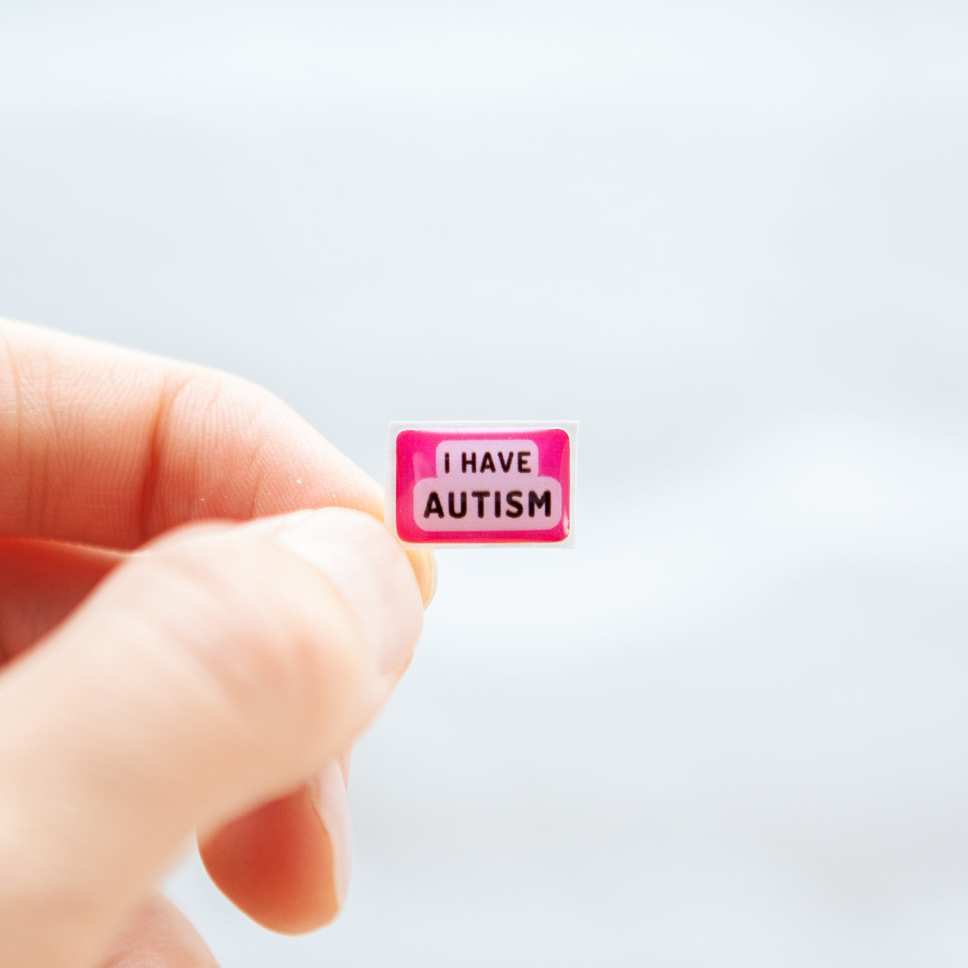 A high-quality autistic sticker with bold text saying "I Have Autism" in pink or blue, designed for name badges and ID badges, promoting autism awareness and inclusivity.
